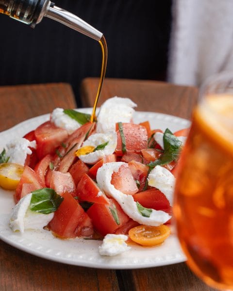 starter tomato salad with olive oil being poured on top