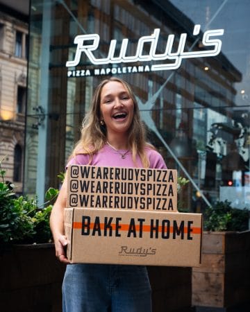 woman smiling and holding bake at home napoli pizza boxes