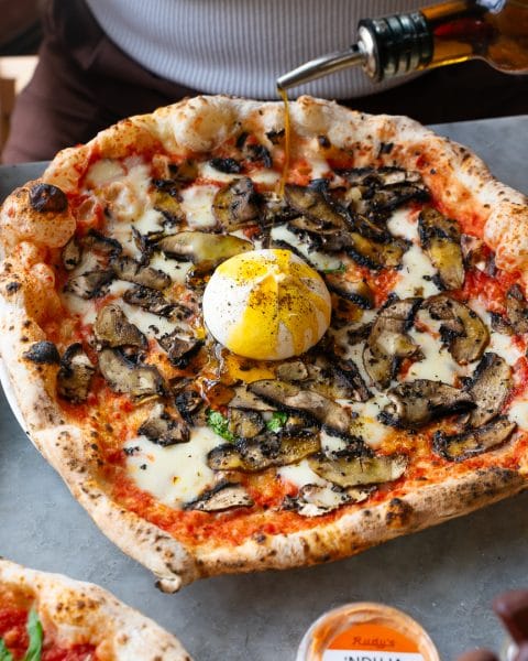 burrata pizza with chilli oil being poured over