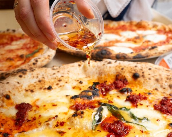 chilli olive oil being poured over pizza with cheese