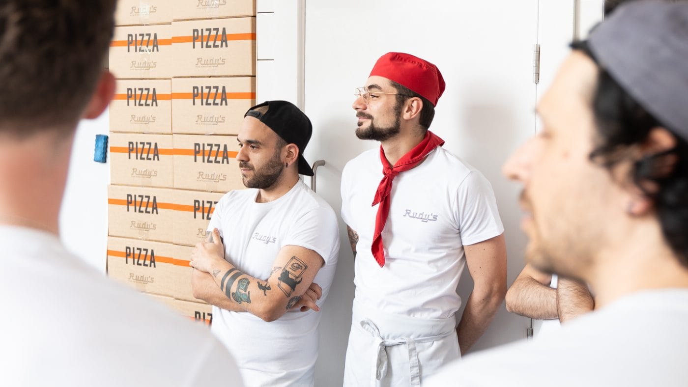 kitchen staff near pizza boxes at rudy's pizza