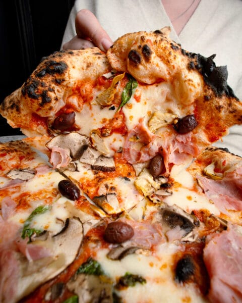 Neapolitan pizza topped with San Marzano tomato, Fior di Latte, Grana Padano, prosciutto cotto, Kalamata olives, portobello mushrooms, artichoke hearts, basil