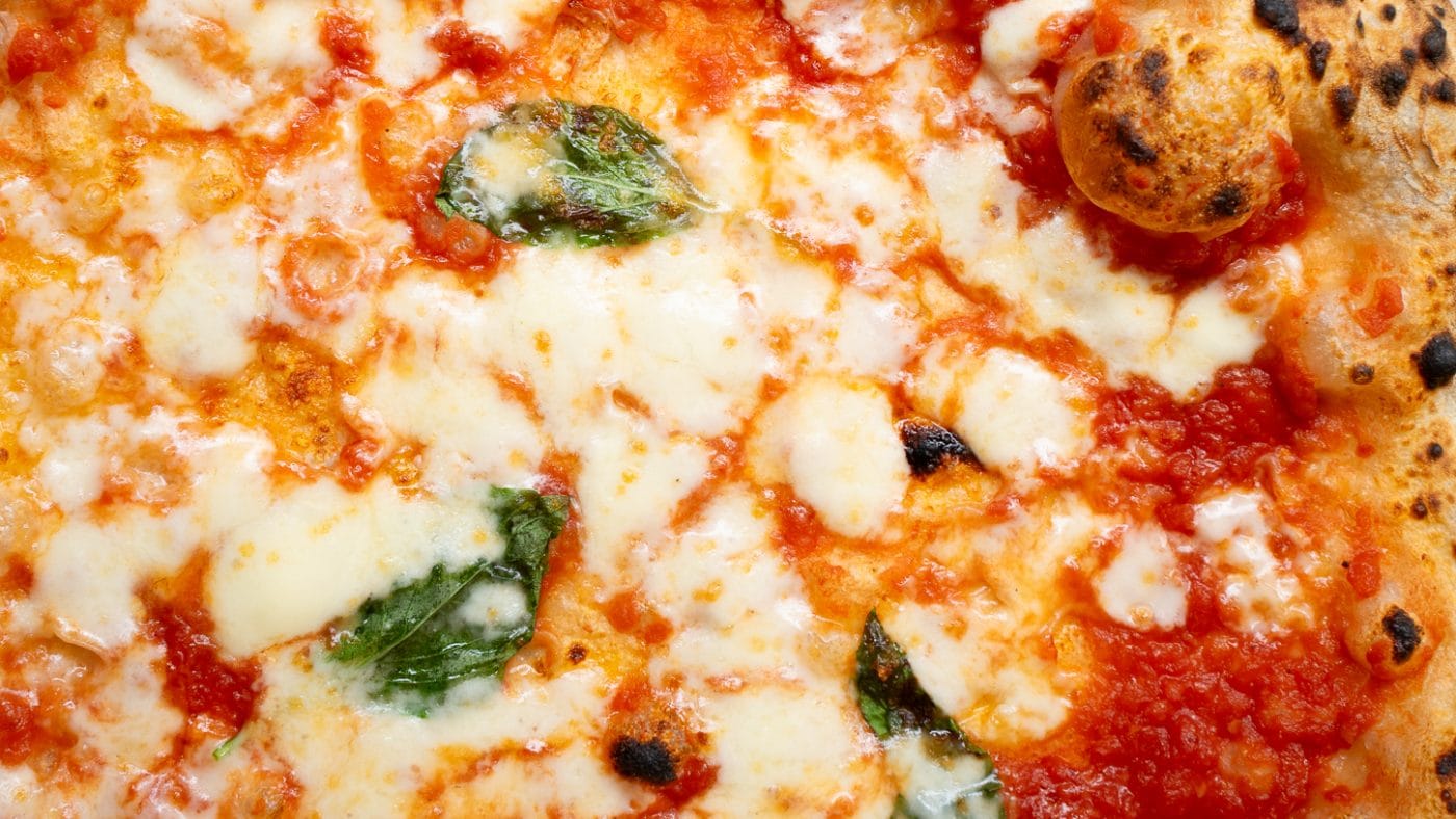 prepared pizza with cheese and tomato base