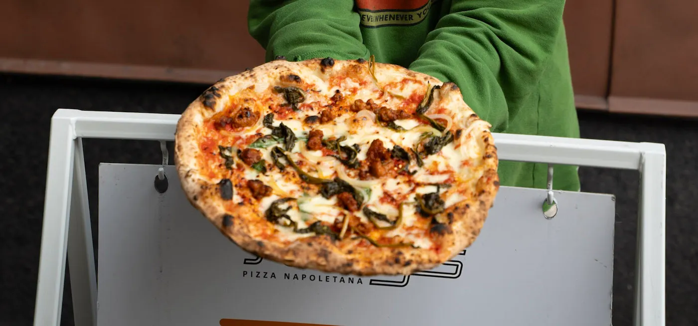 girl holding salsiccia pizza