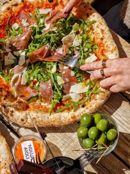 Pizza topped with rocket, Parmesan shavings and prosciutto