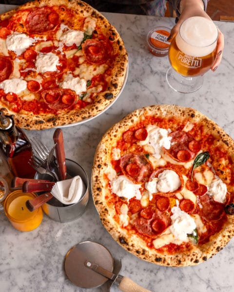Pizza topped with cheese, three types of pepperoni, stracciatella and hot honey