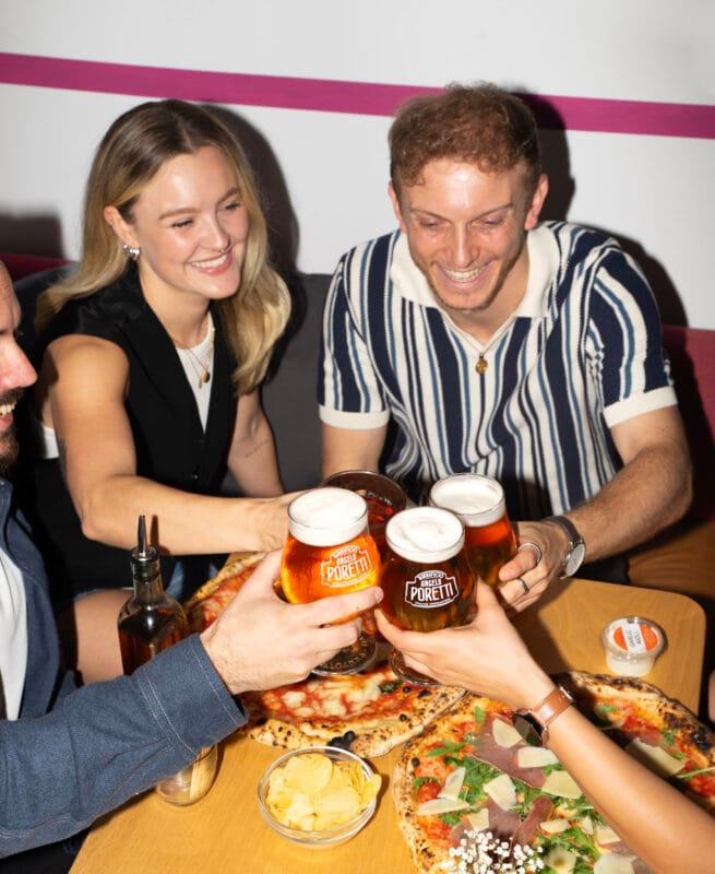 A group of people enjoying proper Neapolitan pizza with fresh ingredients and drinks